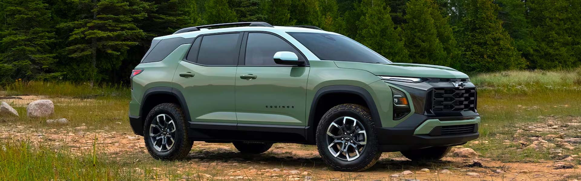 2026 Chevy Equinox compact crossover SUV in green with black roof rails and aggressive grille, parked in nature emphasizing adventure-ready performance and modern SUV styling