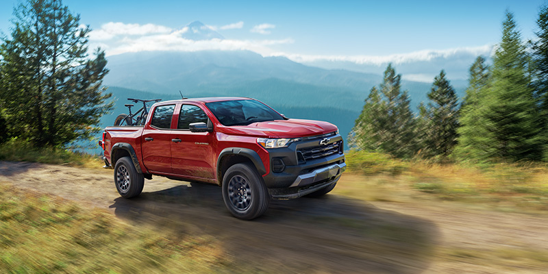 A Chevrolet Colorado driving on a dirt road, showcasing its rugged design and off-road capabilities.